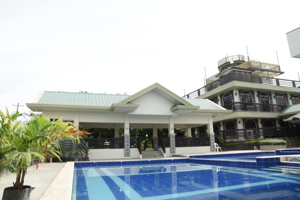 a hotel with a swimming pool in front of a building at Villa Esmeralda Bryan's Resort Hotel and Restaurant in Palayan City