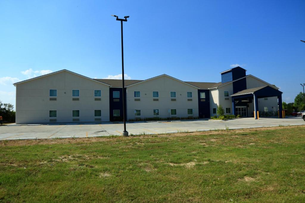 Americas Best Value Inn & Suites-Prairieville في Prairieville : مبنى أبيض كبير مع ضوء الشارع في الأمام