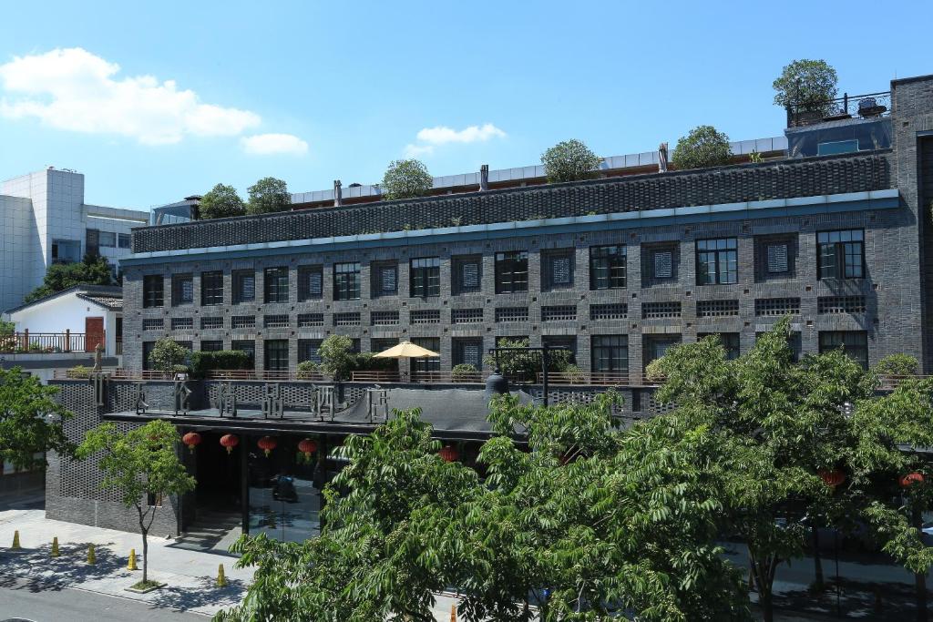 an apartment building with a balcony and trees at Tea Boutique Hotel West Lake in Hangzhou