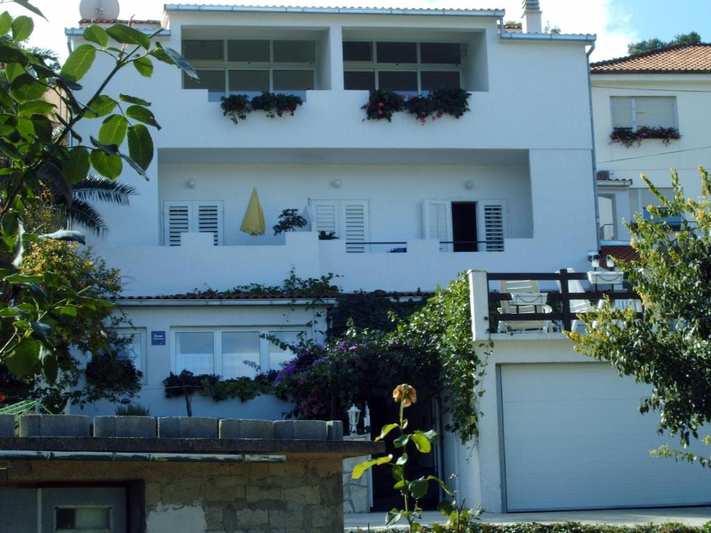 una casa blanca con muchas plantas en Apartments Adria Blue, en Jelsa