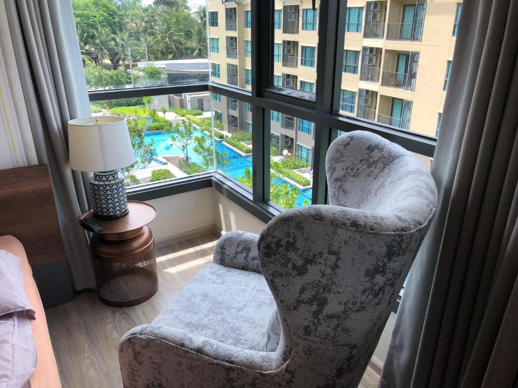 een woonkamer met een stoel en een raam bij rain condo 2 bedroom by leelawadee in Cha Am