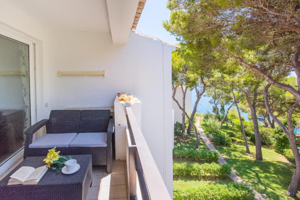 balkon z ławką i stołem z kwiatami w obiekcie Apartamento Ferrera Park 623 w mieście Cala Ferrera