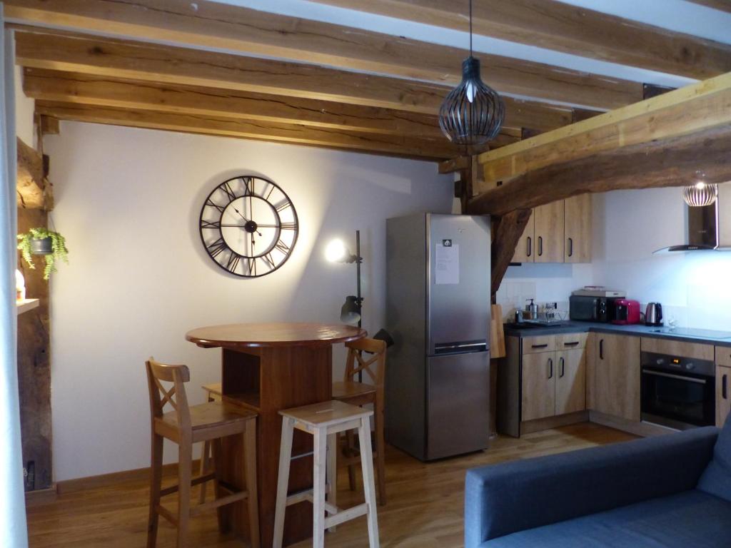 a kitchen with a table and a clock on the wall at La chambre d&#39;Eloi, appart à 5mndu zoo de Beauval- 2e étage in Saint-Aignan