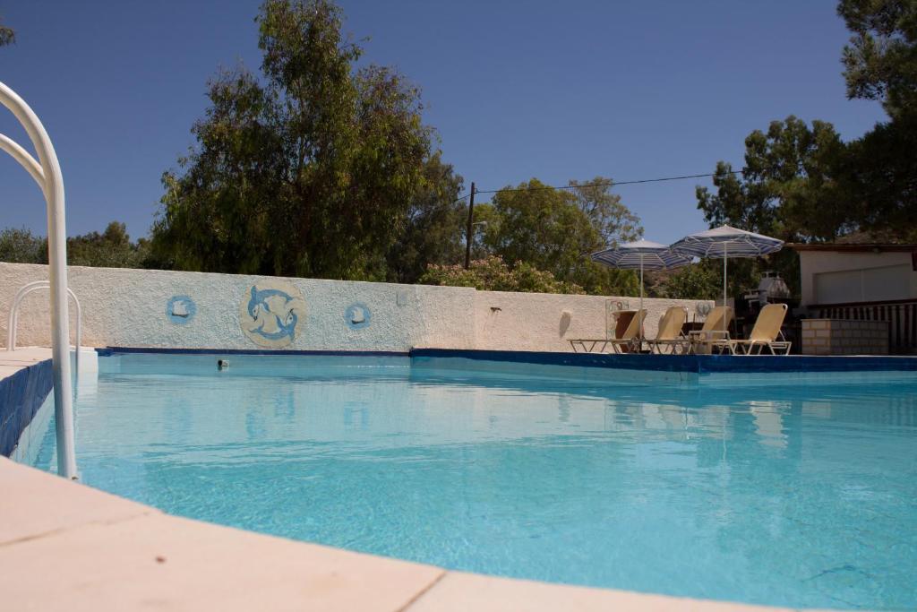 a large swimming pool with chairs and an umbrella at Esperides Hotel in Myrtos