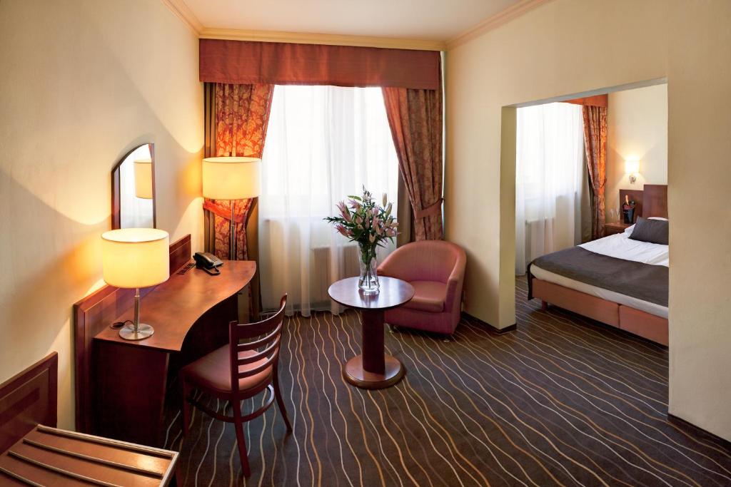 a hotel room with two beds and a table at Luxury Family Hotel Bílá Labuť in Prague