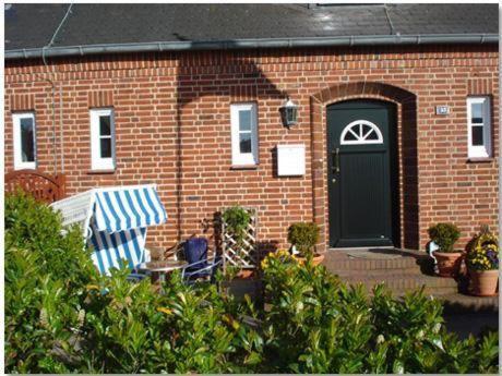 a brick house with a green door and a bench at Austernperle in List