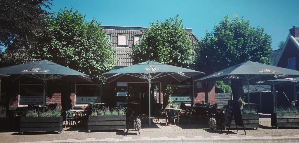 un patio con tavoli e ombrelloni di fronte a un edificio di Café Langelo a Langelo