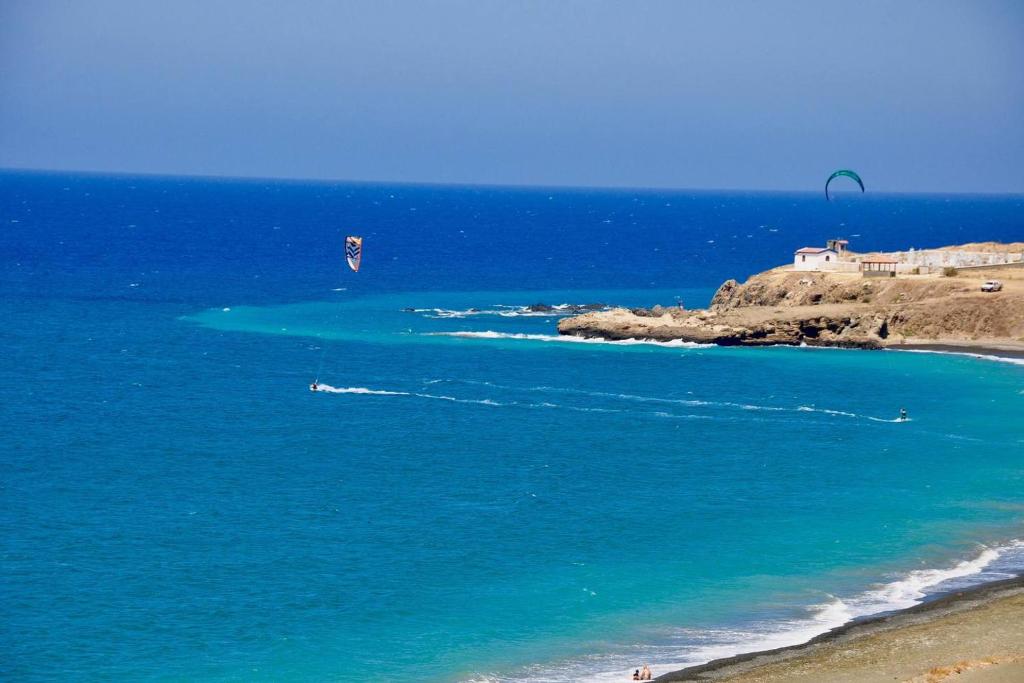 two people kitesurfing in the ocean near a beach at Apartment with stunning sea view in Pachyammos