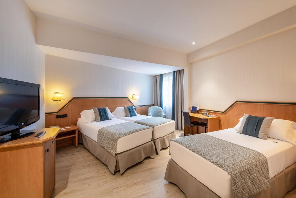 um quarto de hotel com duas camas e uma televisão de ecrã plano em Hotel Praga em Madrid