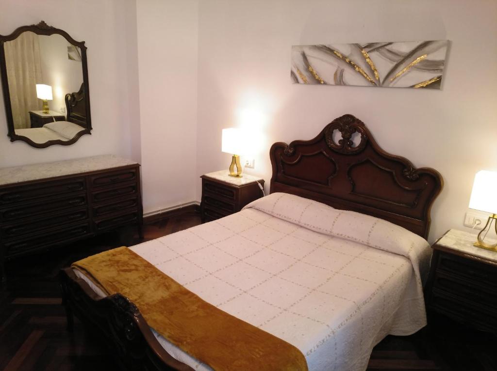 a bedroom with a bed and a mirror and two lamps at Apartamento Ciudad de la Cultura in Santiago de Compostela