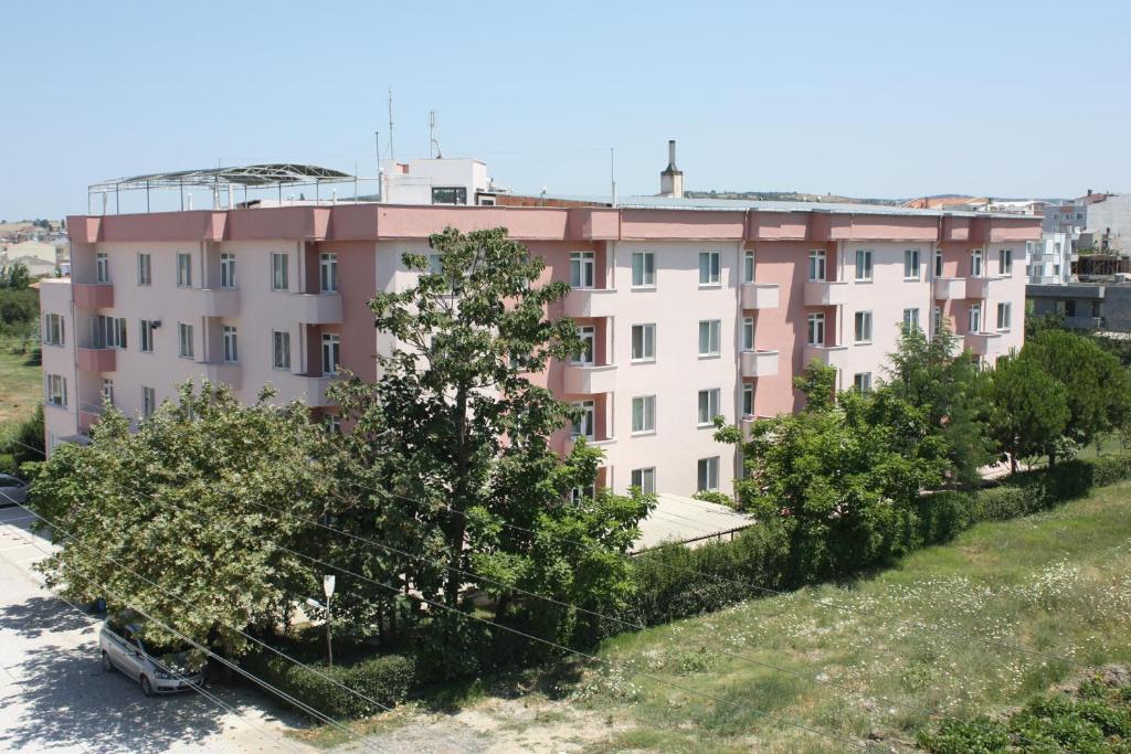 a pink building with trees in front of it at Orçin Apart Hotel in Lapseki