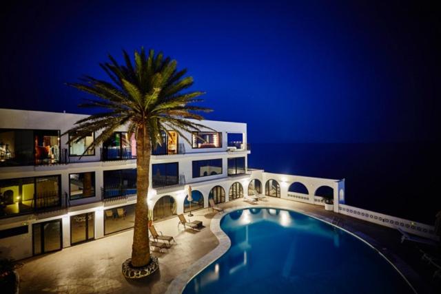 a building with a palm tree next to a swimming pool at Ocean Loft in Maspalomas