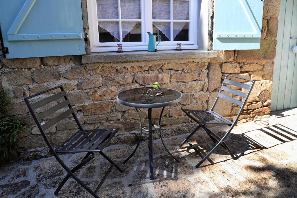 two chairs and a table in front of a brick wall at La petite soixante deux in Le Lonzac