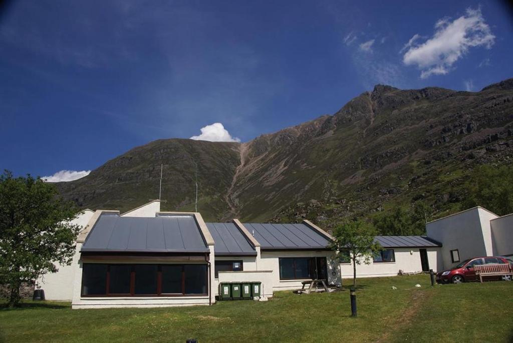 a white house with a mountain in the background at Torridon Youth Hostel in Torridon