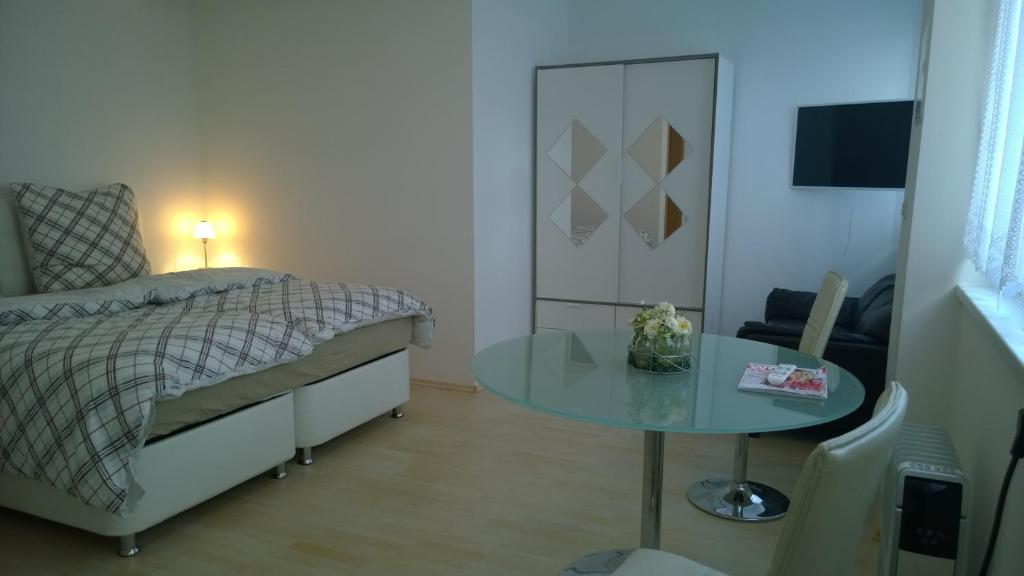 1 dormitorio con cama y mesa de cristal en Pensionsappartments Blitz, en Wiesbaden