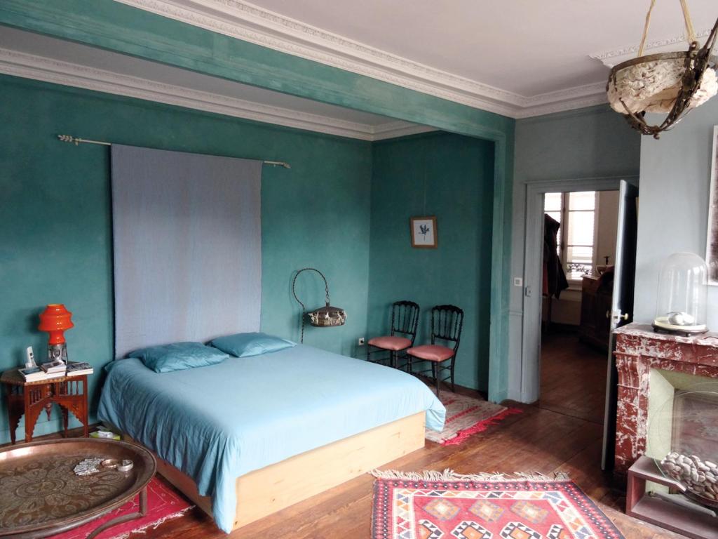 a bedroom with a bed and a green wall at L'escalier des rêves in Saint-Sauveur-en-Puisaye