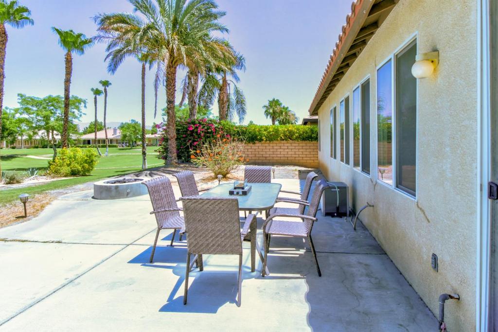 a patio with a table and chairs and palm trees at Paradise in Indian Palm Country Club Permit# 50103 in Indio