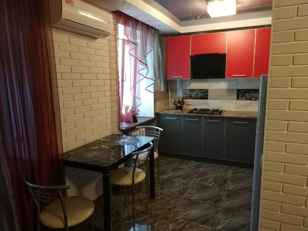 ザポリージャにあるApartment 2Bed Rooms Lux on Gagarina Prospect Soborniyのキッチン(テーブル、椅子、赤いキャビネット付)