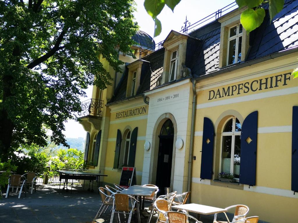 a building with tables and chairs in front of it at Dampfschiff Radebeul-Altkö in Radebeul