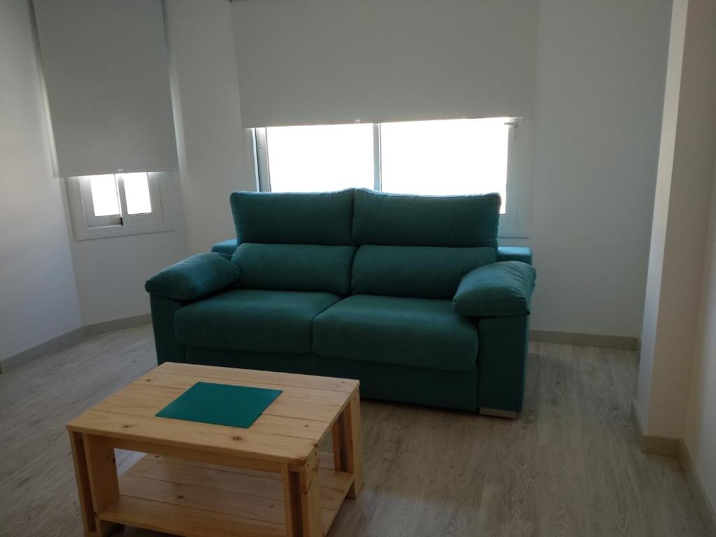 a living room with a green couch and a coffee table at Apartaments Can Fabul in Sant Carles de la Ràpita