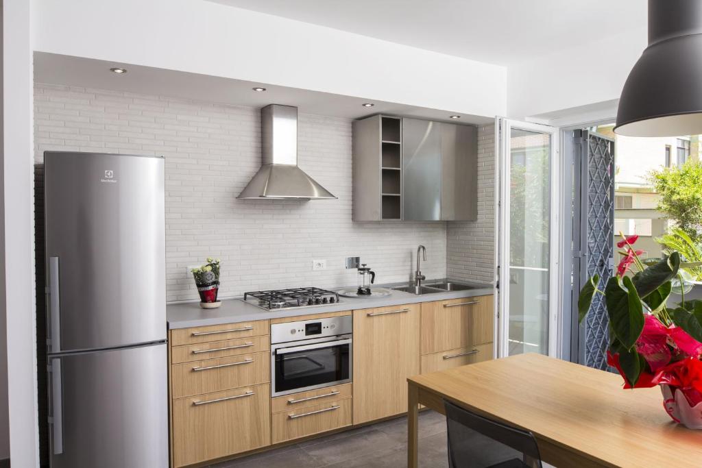 a kitchen with a stainless steel refrigerator and a table at Rosa's House Rome Airport in Fiumicino