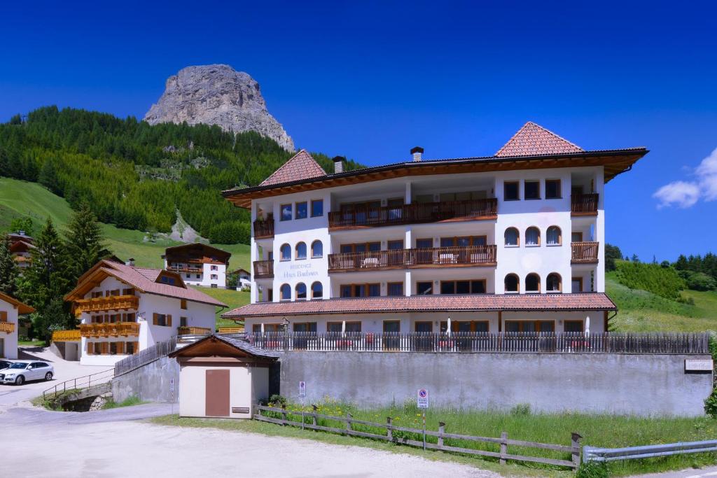 a large white building with a mountain in the background at Residence Barbara in Colfosco