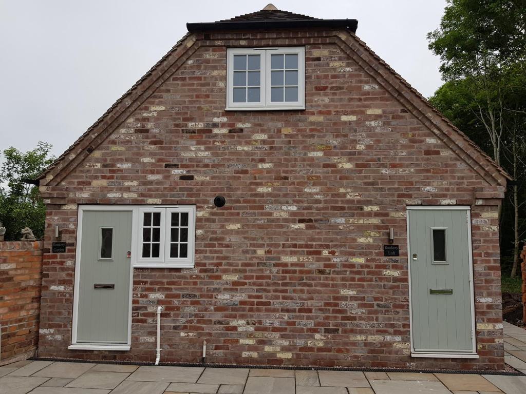 a brick building with two windows and two doors at Rookery Lodge Apartments in Wistaston