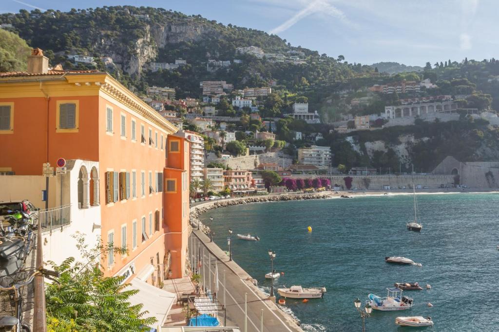 a view of a beach with boats in the water at Résidence Pierre & Vacances l'Ange Gardien in Villefranche-sur-Mer