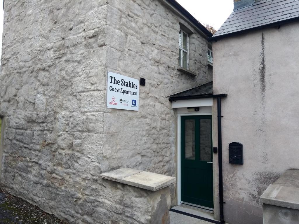 un panneau sur le côté d'un bâtiment avec une porte verte dans l'établissement The Stables Guest Apartment, à Cookstown