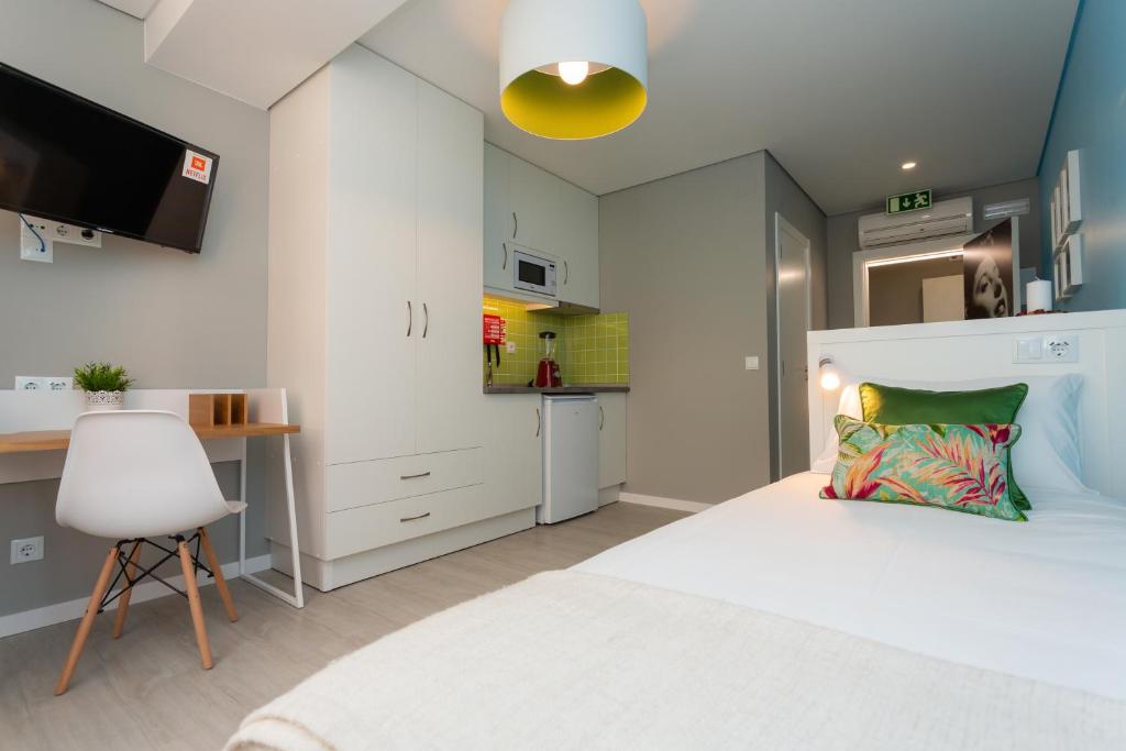 a bedroom with a white bed and a kitchen at Chic Studios in Parede