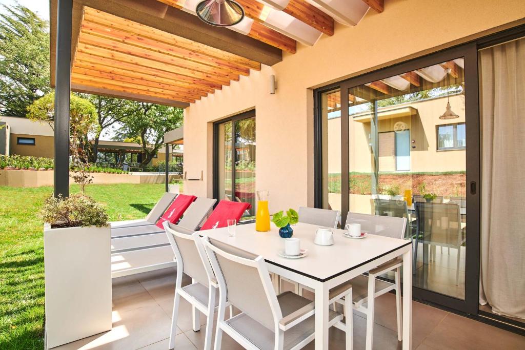 een patio met een witte tafel en stoelen bij Apartments Park Plava Laguna in Poreč