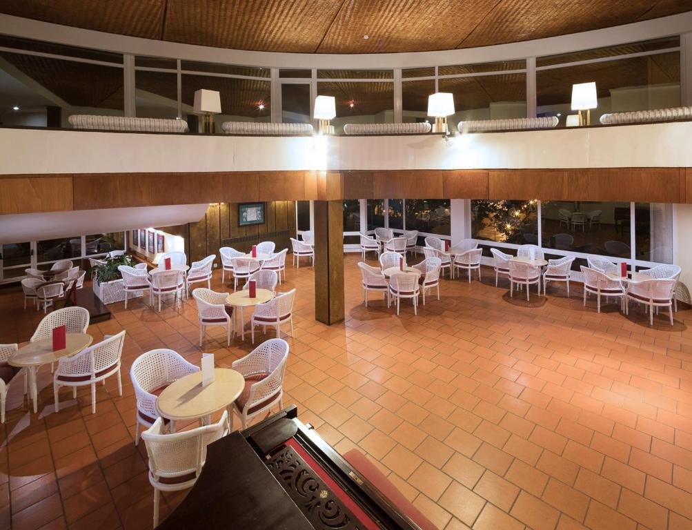 a restaurant with white chairs and tables and tablesktop at Dom Pedro Madeira in Machico