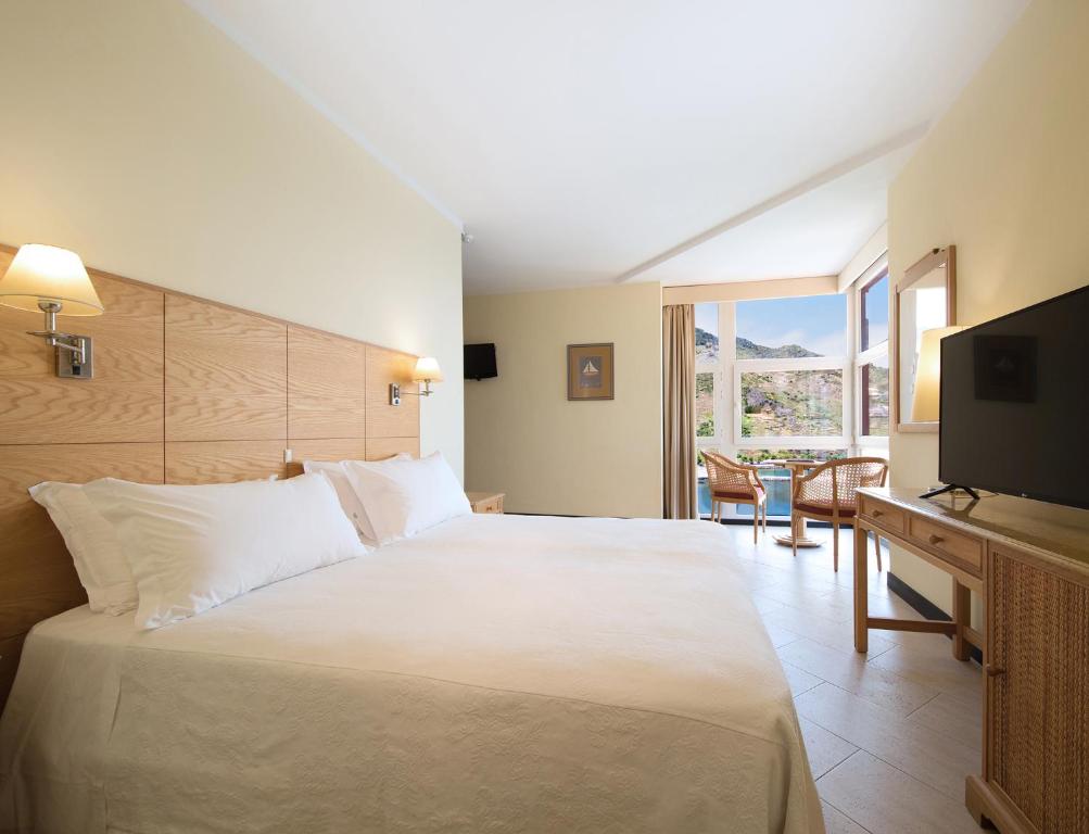 a hotel room with a large bed and a television at Dom Pedro Madeira in Machico
