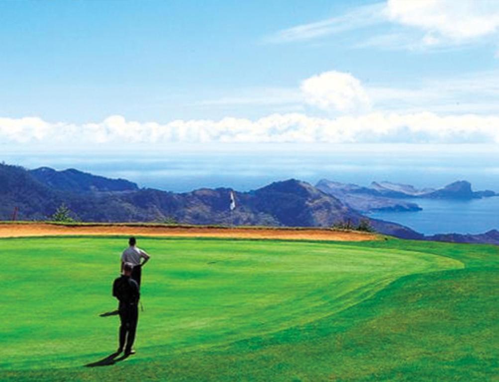 two people standing on top of a green golf course at Dom Pedro Madeira in Machico