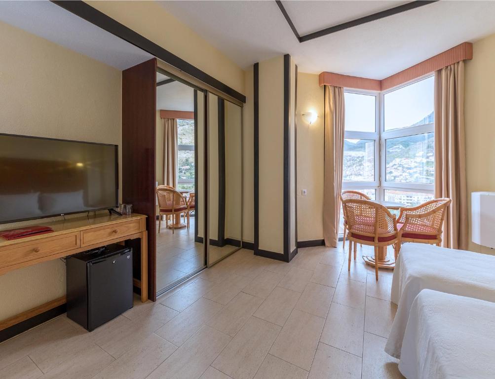 a hotel room with a bed and a television at Dom Pedro Madeira in Machico