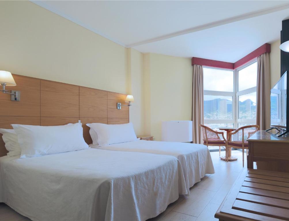 a hotel room with a bed and a large window at Dom Pedro Madeira in Machico