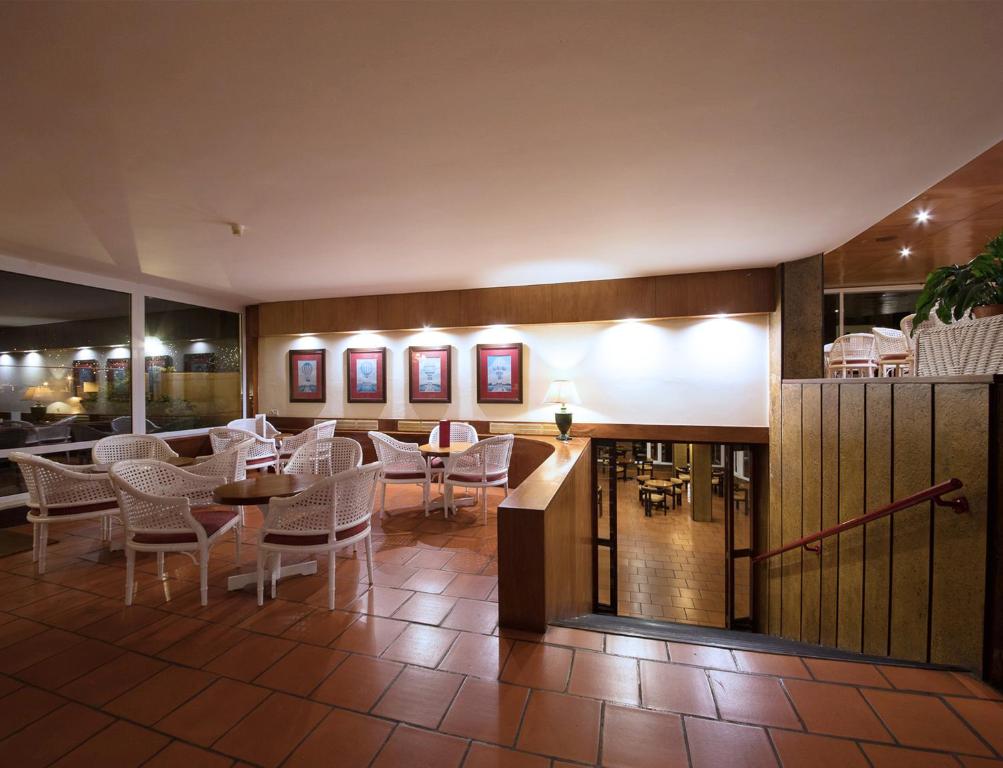 a restaurant with tables and chairs in a room at Dom Pedro Madeira in Machico