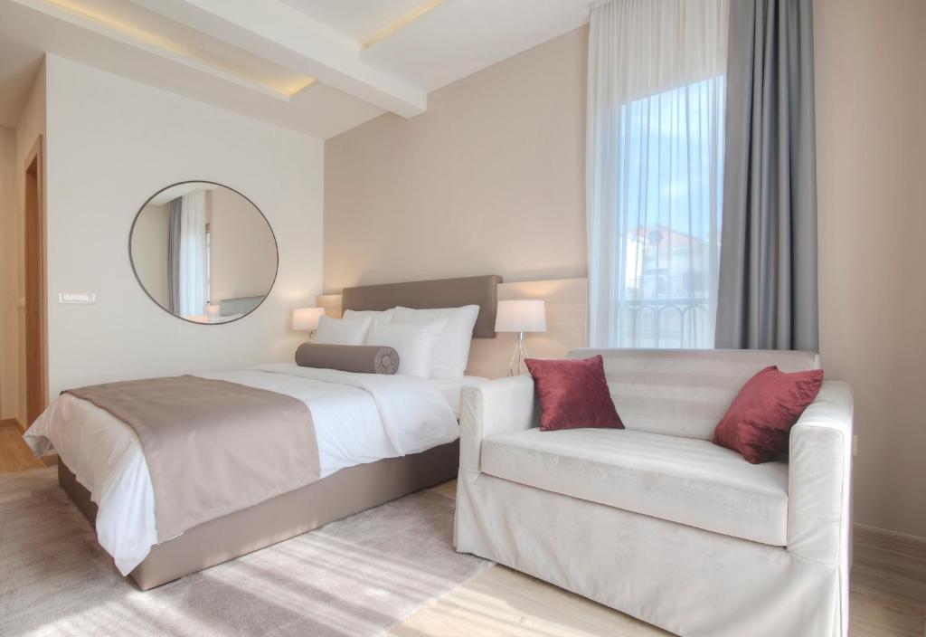 a bedroom with a bed and a chair and a mirror at Hotel Villa Gracia in Budva