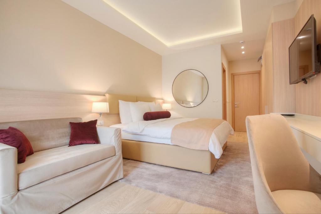 a bedroom with a bed and a couch and a mirror at Hotel Villa Gracia in Budva
