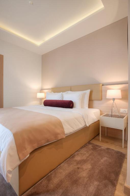 a bedroom with a large bed with a red pillow on it at Hotel Villa Gracia in Budva