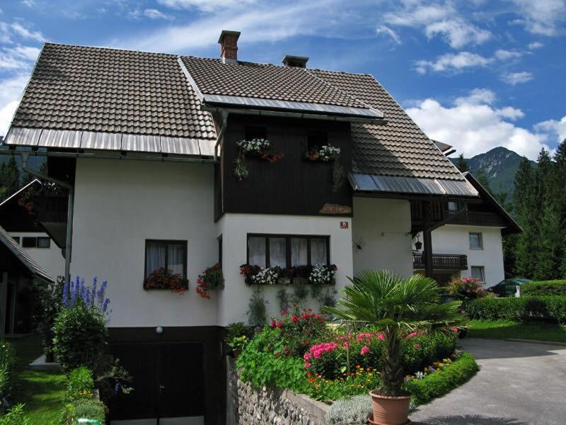 a house with flowers and plants in front of it at Apartment Ticar in Bohinj
