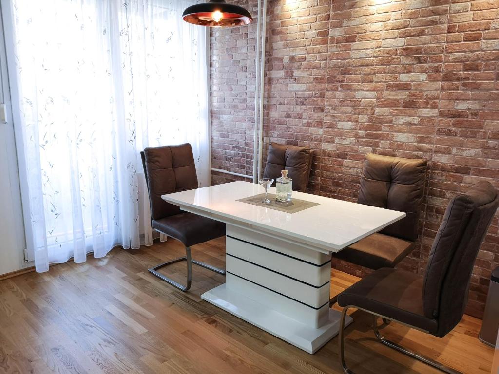 uma mesa branca e cadeiras num quarto com uma parede de tijolos em Apartment Mia -V em Zagreb