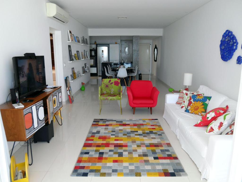 sala de estar con sofá blanco y silla roja en Pitangueiras - Apto. Frente Mar en Guarujá