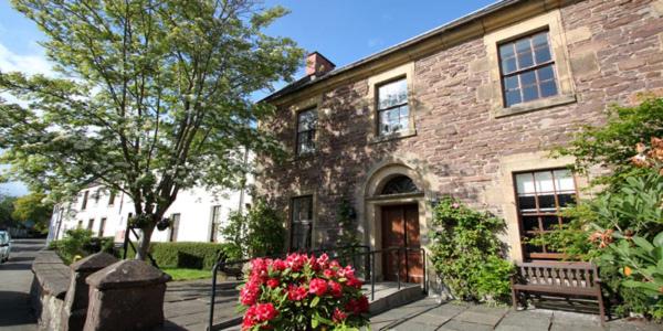 een bakstenen gebouw met een bank ervoor bij Old Churches House in Dunblane