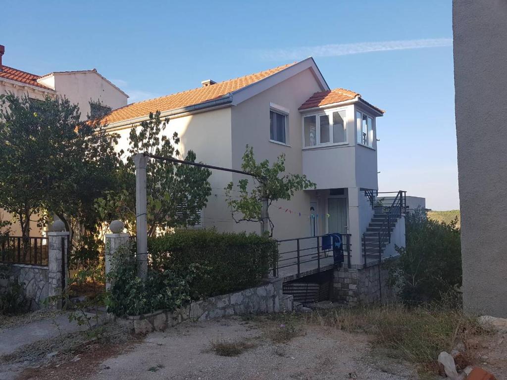 a white house with stairs and a fence at Apartments Maria in Ivanica