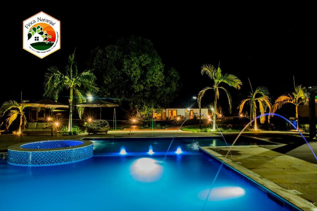 a swimming pool at night with a hotel sign in the background at Hotel Finca Naranjal in Granada
