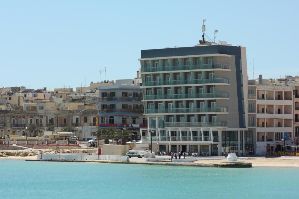 ein Gebäude neben einem Wasserkörper mit Gebäuden in der Unterkunft Water's Edge Hotel in Birżebbuġa