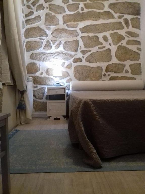 a bedroom with a stone wall and a bed at Casinha de Lamares in Vila Real