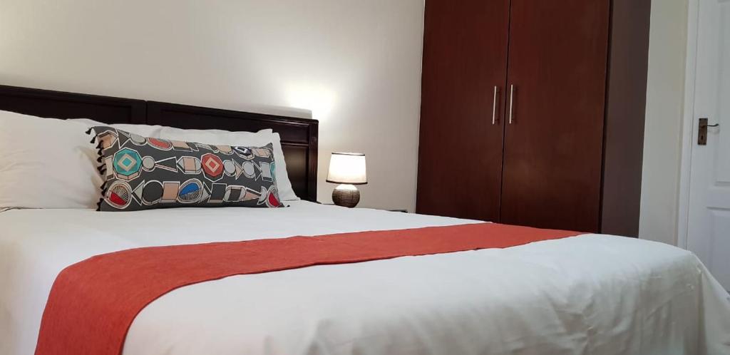 a bedroom with a large white bed with a red blanket at Ocean View Villas Unit G07 in Port Edward