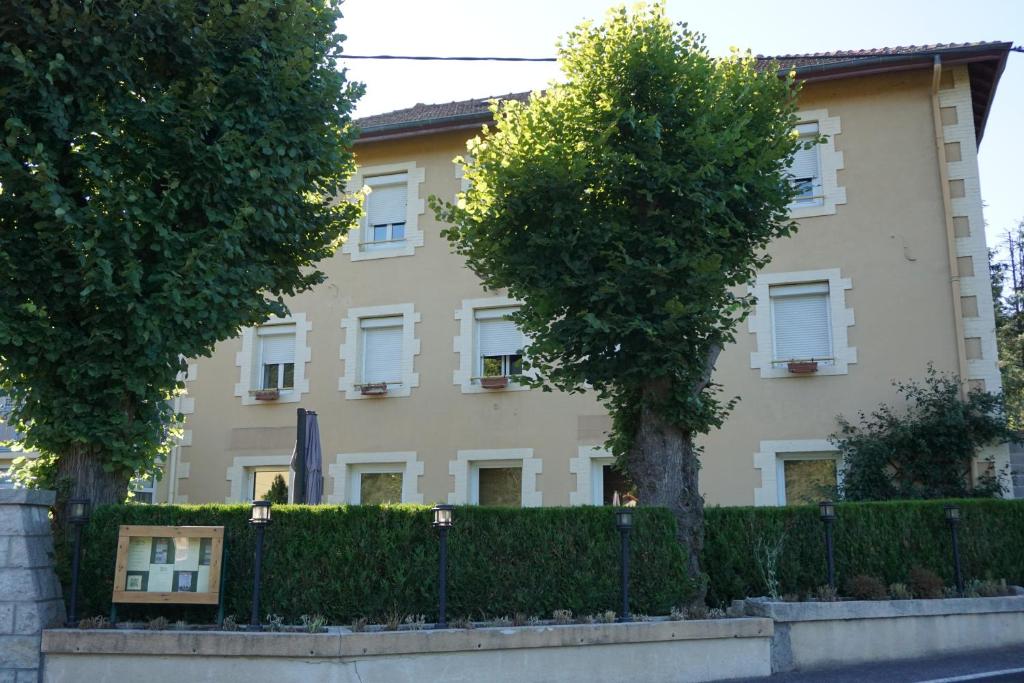 un bâtiment avec deux arbres devant lui dans l'établissement Chambres et table d’hôtes le Barret, à Beauzac